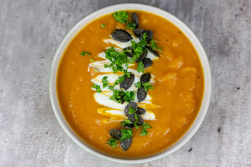 Healthy food - sweet potato cream soup with pumpkin seeds and parsley. Top view