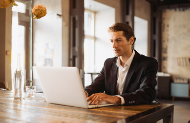 Fototapeta premium Young man drawing template for the web site associated with digital marketing, current trends and tendencies of UX / UI design. Businessman who rules his company remotely, like a freelancer