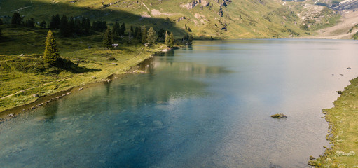 Fototapeta na wymiar Mountain lake with a green meadow
