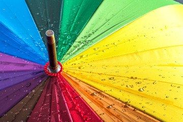 Multi-colored colorful umbrella with all colors of the rainbow with raindrops.