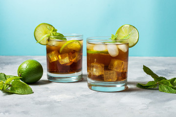 Rum and cola. Cuba Libre drink with lime and ice on rustic concrete table