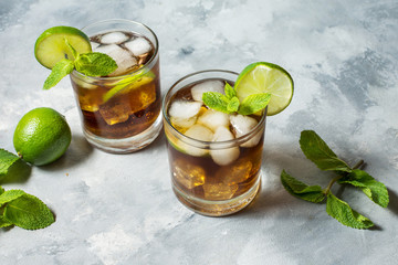 Rum and cola. Cuba Libre drink with lime and ice on rustic concrete table
