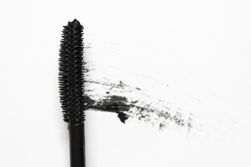 Black mascara and brush on white background. Close up