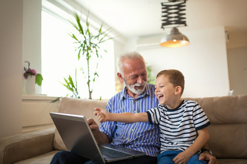 Grandfather and grandson using laptop together