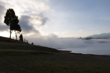 La niebla se levanta del lago conforme amanece y se funde con las nubes en el cielo