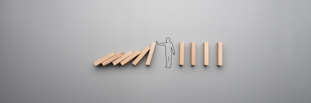 Wide cropped image of the outline of a businessman stopping the domino