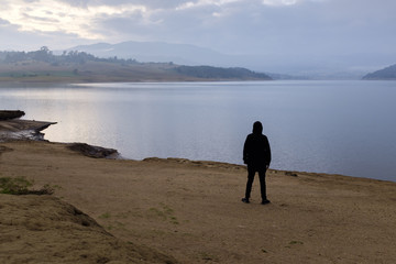 Una persona contempla el amanecer a la orilla del lago