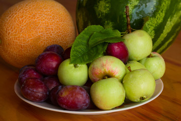 fresh sweet fruits on a plate on a wooden table
