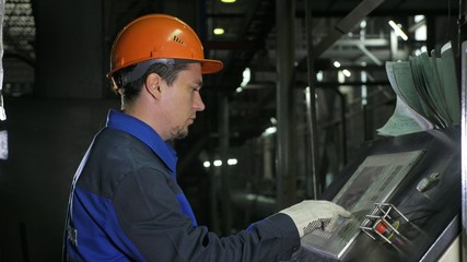 Operator monitors control panel of production line. Manufacture of plastic water pipes of the factory. Process of making plastic tubes on machine tool with the use of water and air pressure.