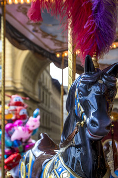 Beautiful colorful black wooden horse with red feathers on head on carousel merry-go-round, amusement on Piazza della Repubblica,  Florence, Italy