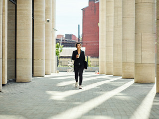 Elegant woman with coffee walking on passage