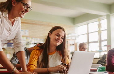High school teacher helping student in classroom