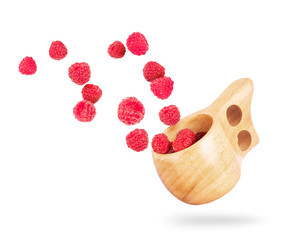 Raspberries fly out of a wooden cup on white background