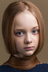 Close-up portrait of beautiful young redhead in studio on beige background.