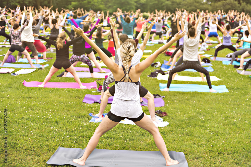 Wall mural big group of adults attending a yoga class outside in park