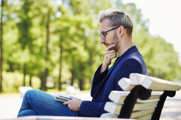 Fototapeta premium Man with notebook thinking sitting on bench