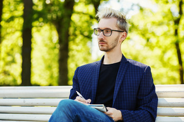 Obraz premium Pensive�man with notepad sitting on bench