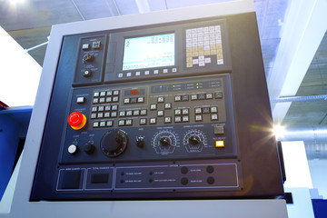 Close up of control panel of CNC machine with adjustment controls and push buttons