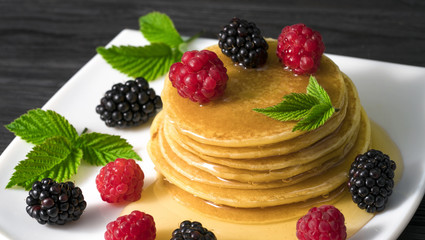 .American pancakes with honey blackberries and raspberries on a dark table