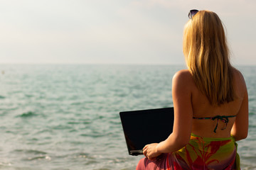 girl working with laptop on the sea