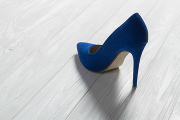 Single high heel shoe on wooden background