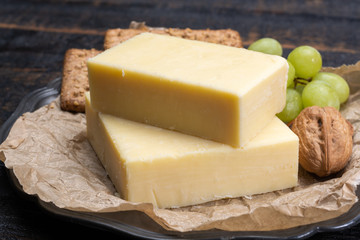 Block of aged cheddar cheese, the most popular type of cheese in United Kingdom and USA, natural cheese made from cow milk - obrazy, fototapety, plakaty