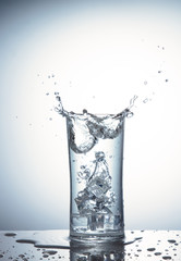 Falling ice cubes in a glass of water with splash