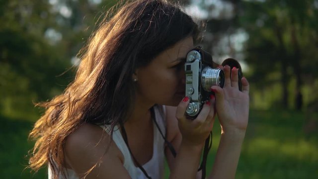 Young woman photographer taking pictures and photos with camera outdoors.