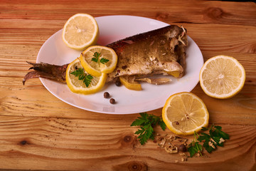 Grilled fish with herbs and lemon on wooden background. Mediterranean luxurious seafood concept