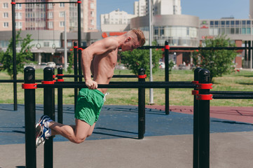 A young guy on a street Playground engaged in sports on bars - 212826449