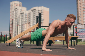 Sports man on the street Playground engaged in sports and push-UPS from the floor - 212826476