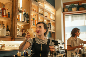 Smiling young female bartender making cocktails in a bar 