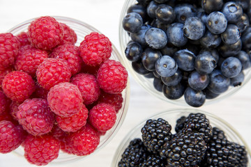 Full bowls of blueberries, blackberries, raspberries, view from above. Healthy eating and dieting. Top view, overhead. Closeup.
