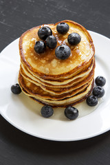 Pancakes with blueberries and honey over black background, side view. Close up.