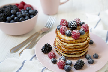 Pancakes with raspberry, blackberry ,blueberry on white wooden table, side view. Closeup.
