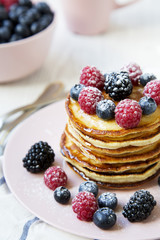Pancakes with raspberry, blackberry ,blueberry on table, side view.