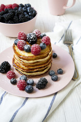 Pancakes with various berries on table, side view. Close-up.