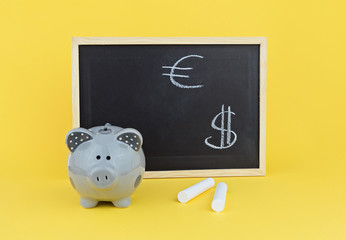 Funny pig piggy bank on background of chalk board with signs of the Euro and Dollar. Concept of...