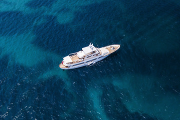 Fototapeta premium Aerial view of a luxury yacht on a turquoise and transparent sea. Emerald Coast, Mediterranean sea, Sardinia, Italy.