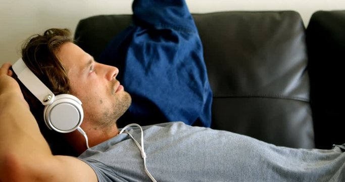 Man listening music on headphones living room 4k