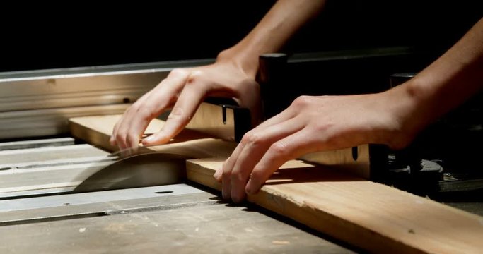 Female welder using table saw on a wooden plank in workshop 4k