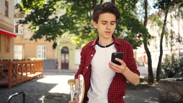 Cute boy using a mobile phone walk keeps skate guy business fashion hand child sun man nature internet social smartphone lifestyle smart teenager young cell communication slow motion