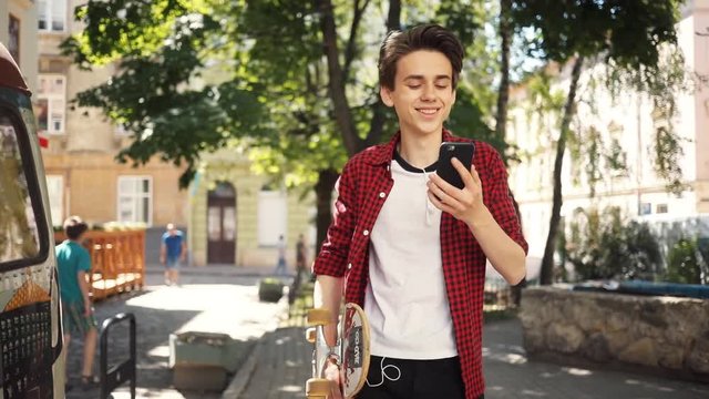 Happy boy using a mobile phone walk keeps skate guy business fashion hand child sun man nature internet social smartphone lifestyle smart teenager young cell communication slow motion