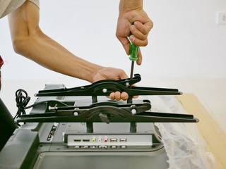 A technician is installing a wall mount on a television getting it ready to be put on a wall