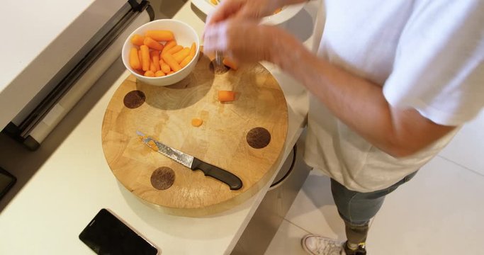 Woman with prosthetic leg cutting carrot on chopping board 4k