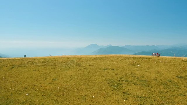 Aerial view people walking on mountain with view of lake Garda and peaks.