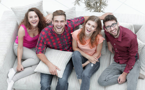 four happy friends laughing while sitting on the couch