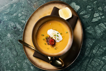 Lentil cream soup with baked lamb, cream fresh and spearmint. Delicious healthy soup food in bowl plate on table background, close-up, top view