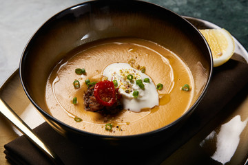 Lentil cream soup with baked lamb, cream fresh and spearmint. Delicious healthy soup food in bowl plate on table background, close-up, top view