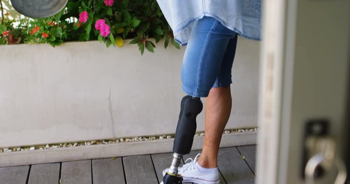 Disabled woman watering plants in the porch 4k